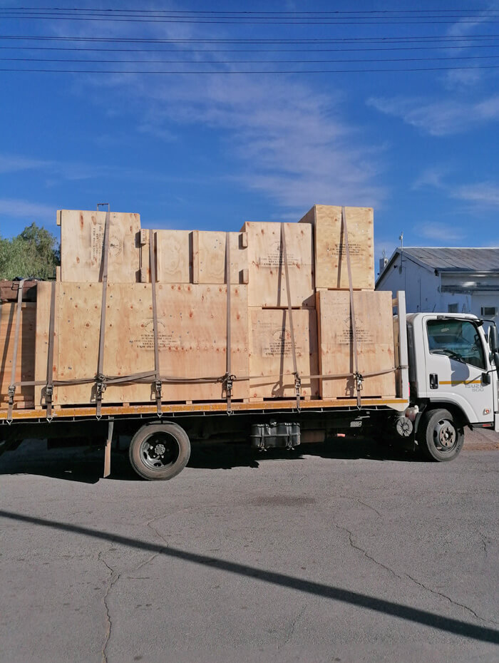 Strapped plywood export crates loaded onto a flatbed truck for collection